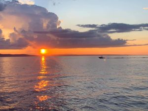 sunset over Lake Champlain with boat moving left across photo